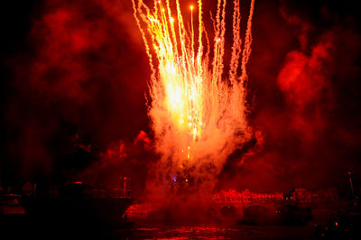 Firework display over moored boats on river at night