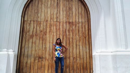 Young woman standing by closed wooden doors