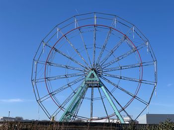 Low angle view of ferris wheel against blue sky