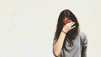 Front view of displeased young woman against white wall