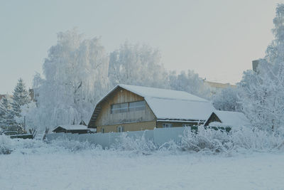 Houses on snow covered landscape against clear sky