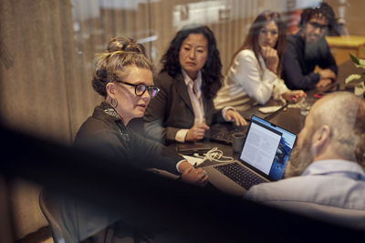 Businesswoman discussing with businessman by colleagues in board room