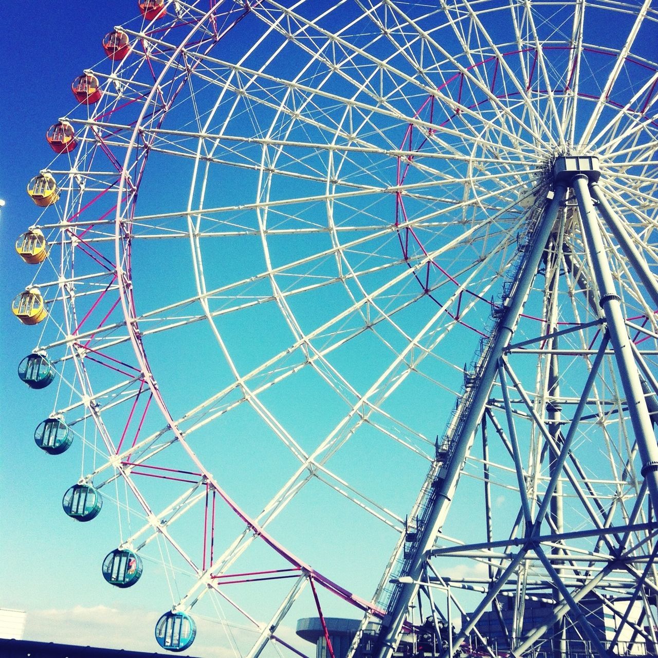 amusement park, ferris wheel, amusement park ride, low angle view, arts culture and entertainment, sky, blue, fun, metal, built structure, clear sky, big wheel, enjoyment, day, outdoors, pattern, architecture, large, no people, metallic