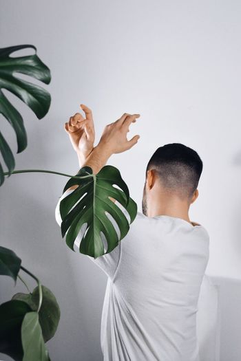 Young man holding white plant against wall