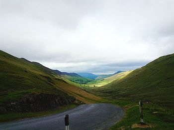 Country road against cloudy sky