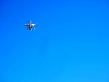 Low angle view of airplane flying against clear blue sky