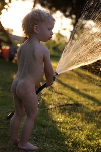 Side view of shirtless boy standing on field