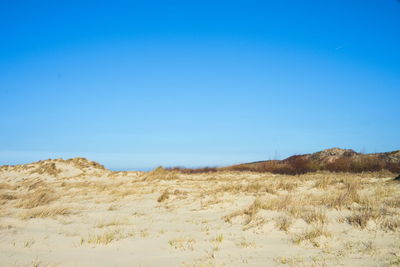 Scenic view of desert against clear blue sky