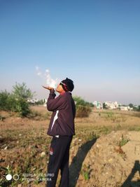 Rear view of man standing on field against clear sky