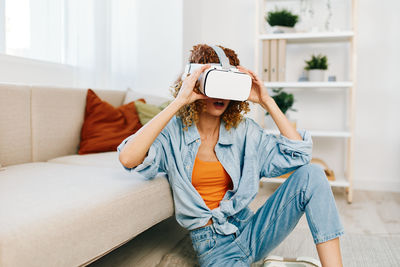 Young woman using phone while sitting on sofa at home