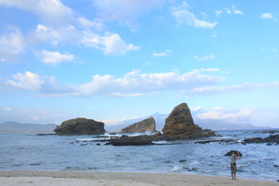 View of calm beach against cloudy sky