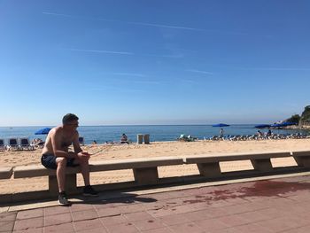 Full length of woman sitting on beach against sky