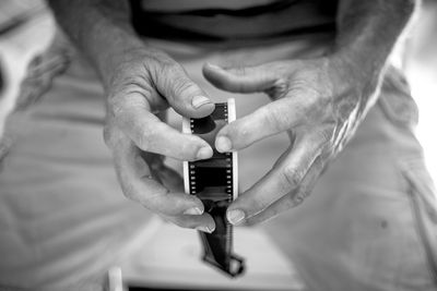 Midsection of man rolling film reel