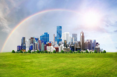 Rainbow over city buildings against sky