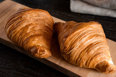 Two croissants on a wooden cutting board. rustic dark table. food series. tasty fresh croissant, jam