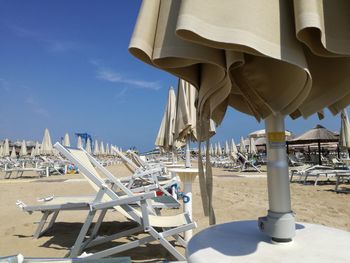 Deck chairs and parasols on beach against sky