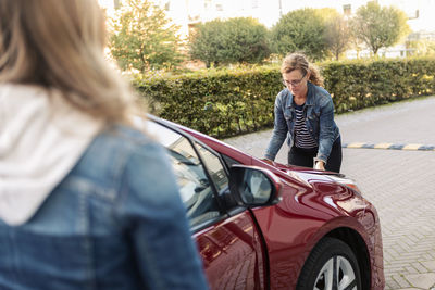 Single mother opening car engine at roadside