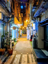 Empty alley amidst buildings in city at night