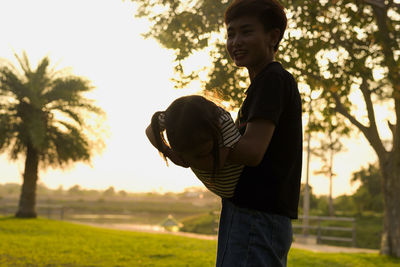 Side view of young man standing against sky during sunset