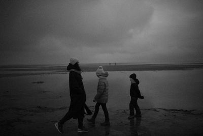 Rear view of people on beach against sky