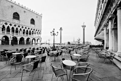 Chairs and tables at sidewalk cafe against buildings in city