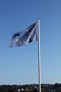 Low angle view of flag against clear blue sky