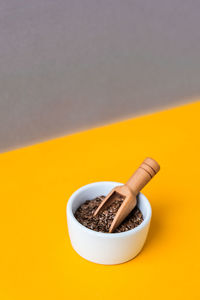 Wooden spoon with flax seeds lies in a white mortar on a yellow background. healthy eating. keto