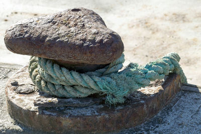 Close-up of rope tied on rusty bollard during sunny day