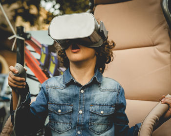 Boy wearing virtual simulator while sitting outdoors