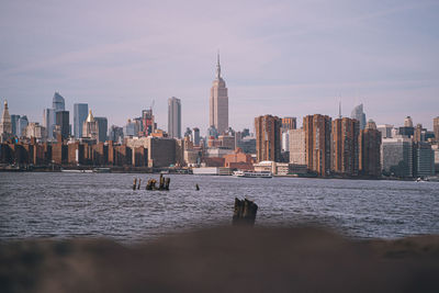 Sea and buildings in city against sky