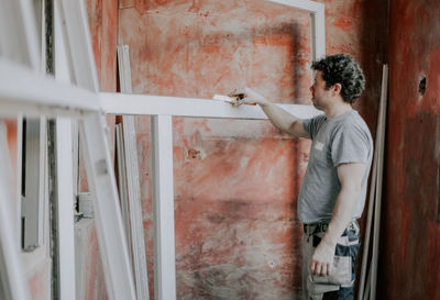 Caucasian male builder clean the window frame.