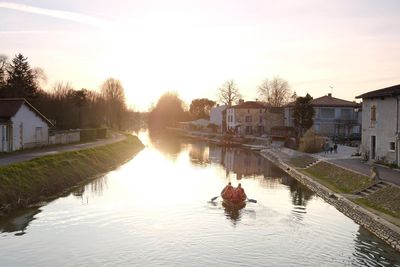 Reflection of houses and trees on river against sky