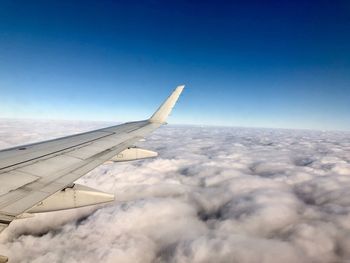 Airplane flying over cloudscape against blue sky