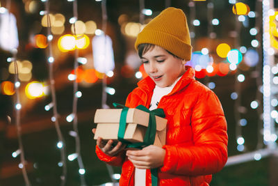 Portrait of a happy boy standing on the evening street and opening a christmas gift. christmas gifts