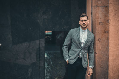 Portrait of young man standing against wall