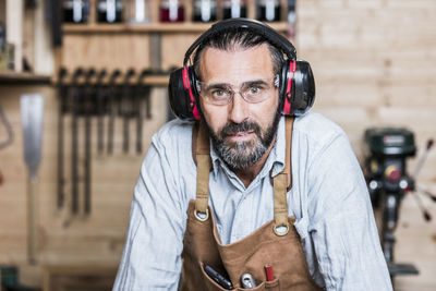 Portrait of carpenter listening music in workshop