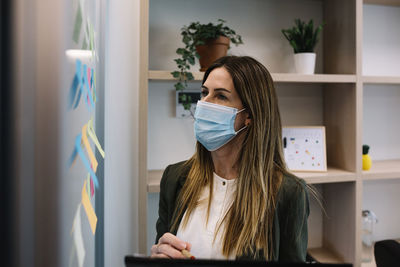 Concentrated businesswoman with protective face mask working at office