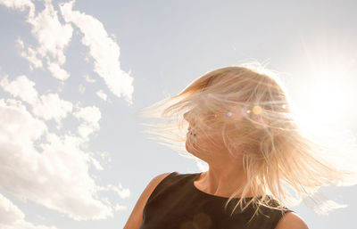 Woman with tousled hair against sky during sunny day