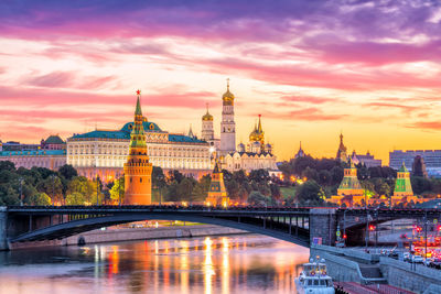 Bridge over river in city against sky during sunset