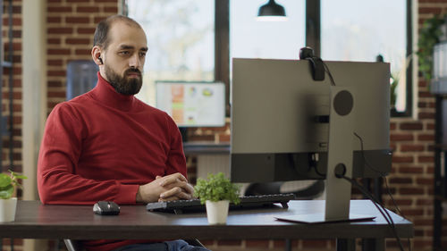 Businessman looking at desktop pc sitting in office