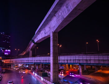 Illuminated bridge over road against sky at night