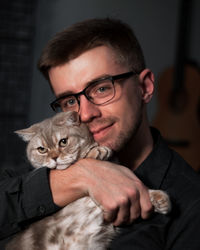 Portrait of young man with cat at home