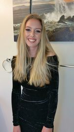 Portrait of smiling young woman standing against wall