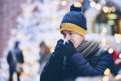Man having drink while standing in city during winter