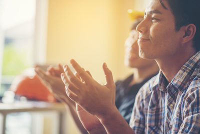 Business colleagues clapping while looking away in office