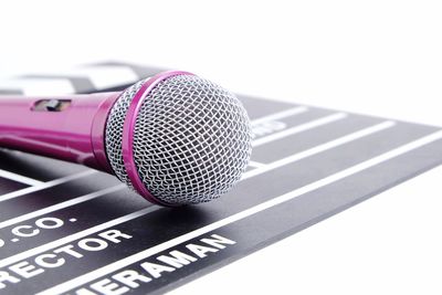 Close-up of microphone with film slate over white background