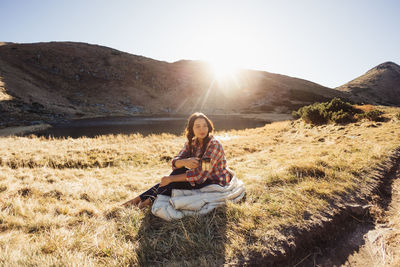 Full length of woman sitting on grass against sky