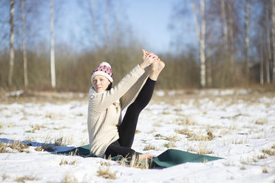 Young attractive woman practicing yoga on snowy field. outdoor sport activity. practice yoga asana. 