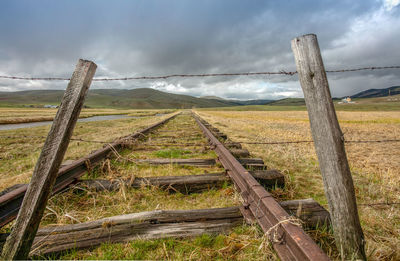 Wooden fence on field against sky