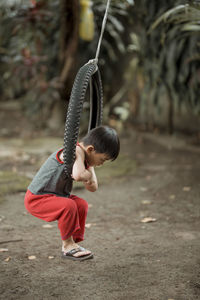 Full length of cute boy hanging on tire swing